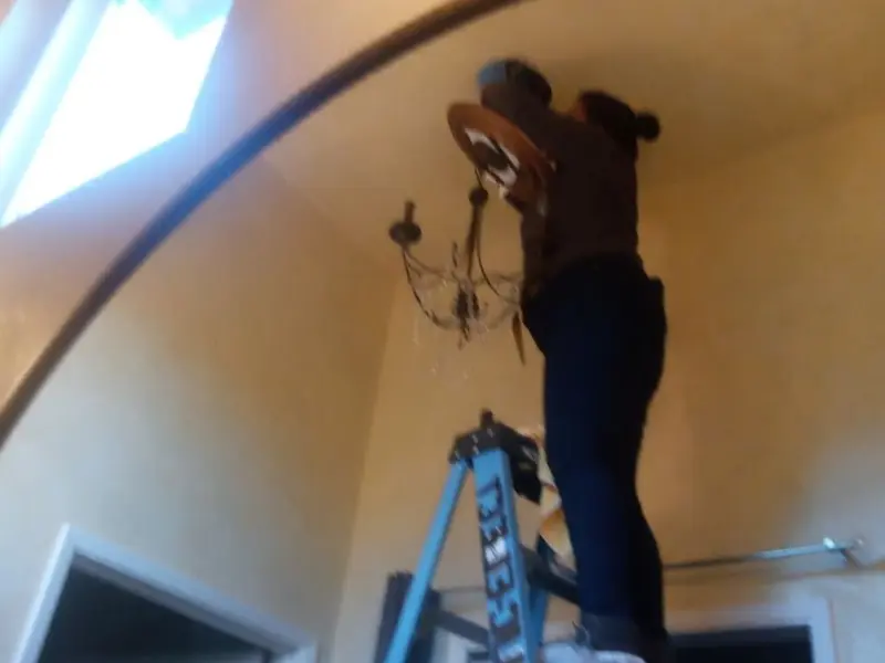 Electrician installing a chandelier in a Alturas residence